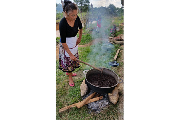 A Woman Cooking in the Open With a Pot on Fire